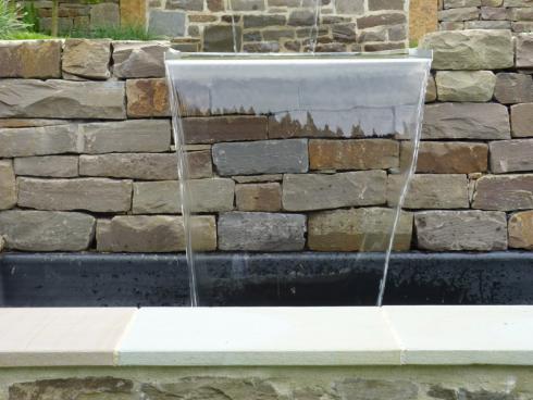 Bild BGL: Wo möglich und gewünscht, kann in die Natursteinmauer ein Wasserfall integriert werden, der Bewegung und Atmosphäre schafft.