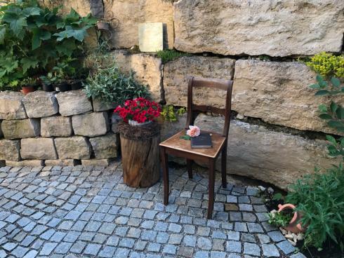 Bild garten.ch: Sitzecke mit leichtem mobilem Stuhl neben Hochbeet mit Blockstein-Einfassung.